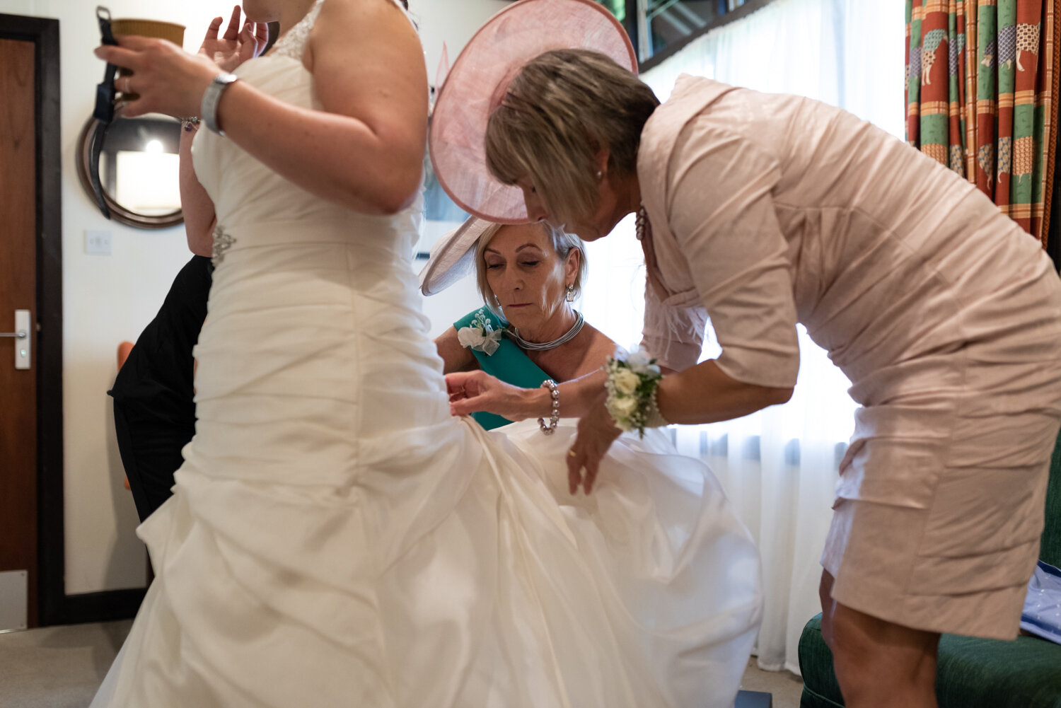 Brides dress being done up by mother and aunty