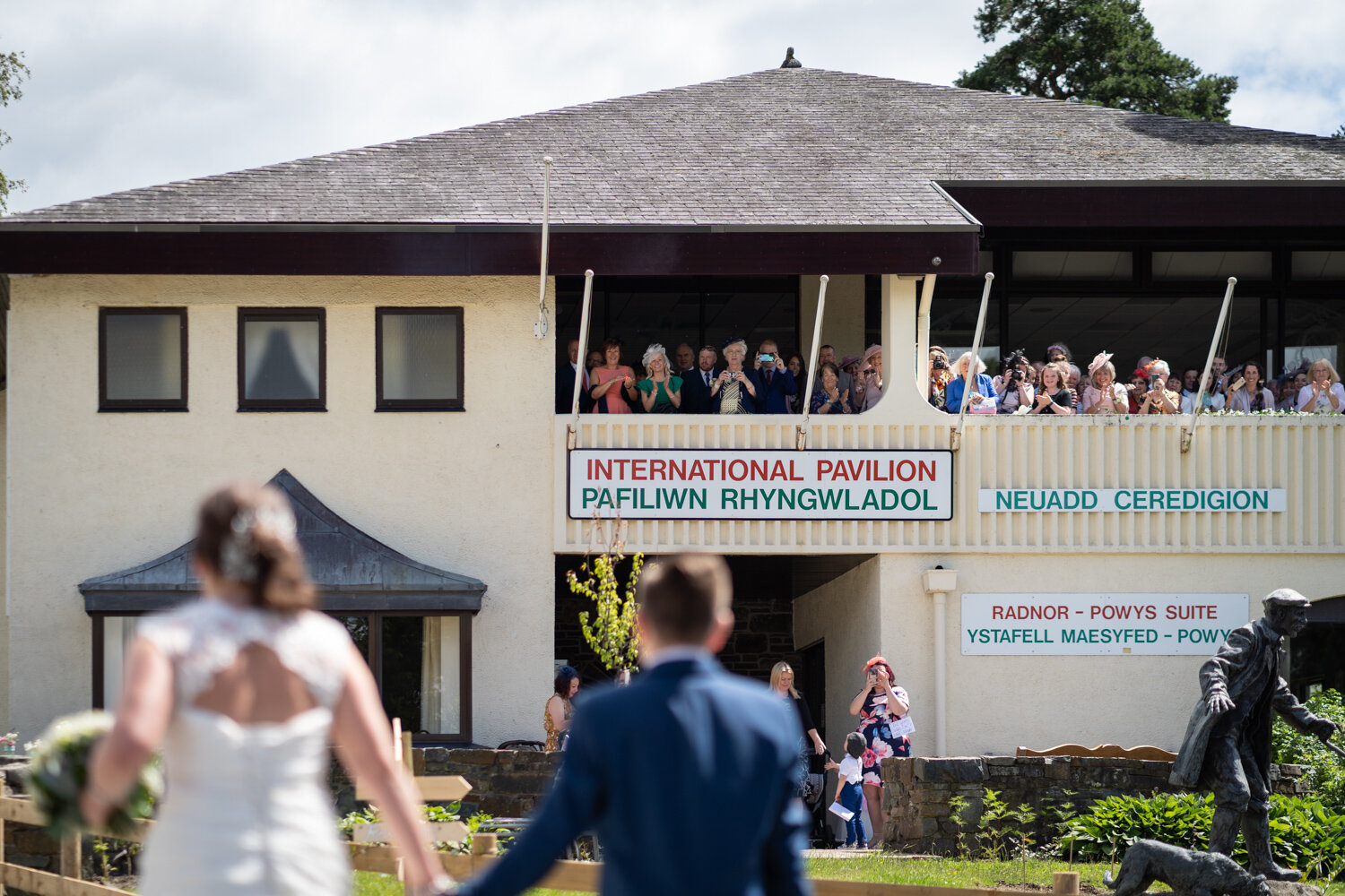 Wedding guests on balcony looking at bride for first time