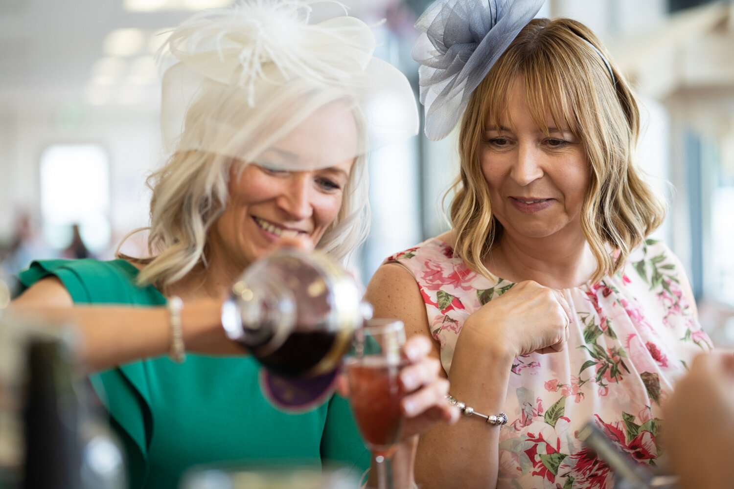 Wedding guests laughing whilst pouring a drink