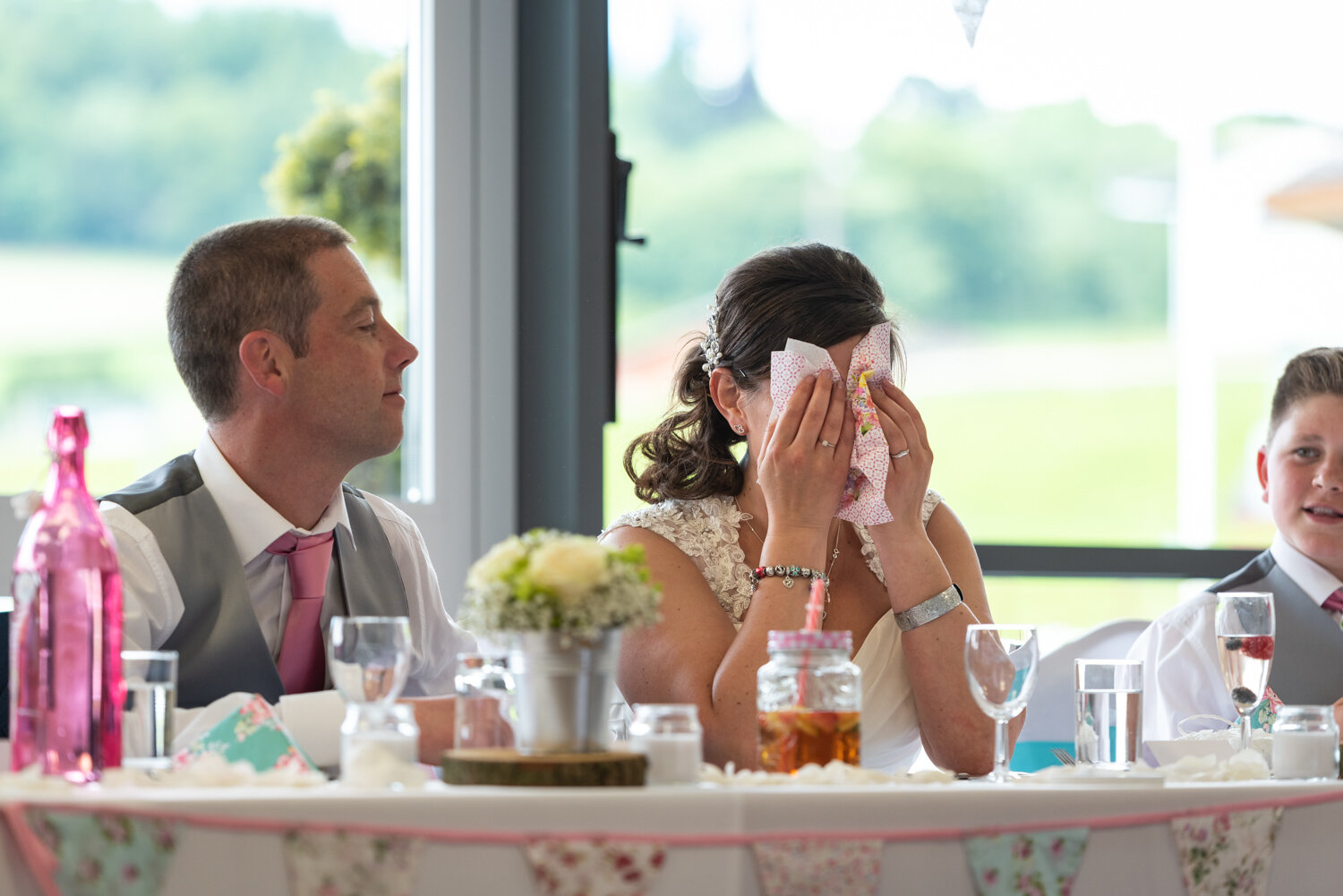 Bride covering her eyes as she cries during speech
