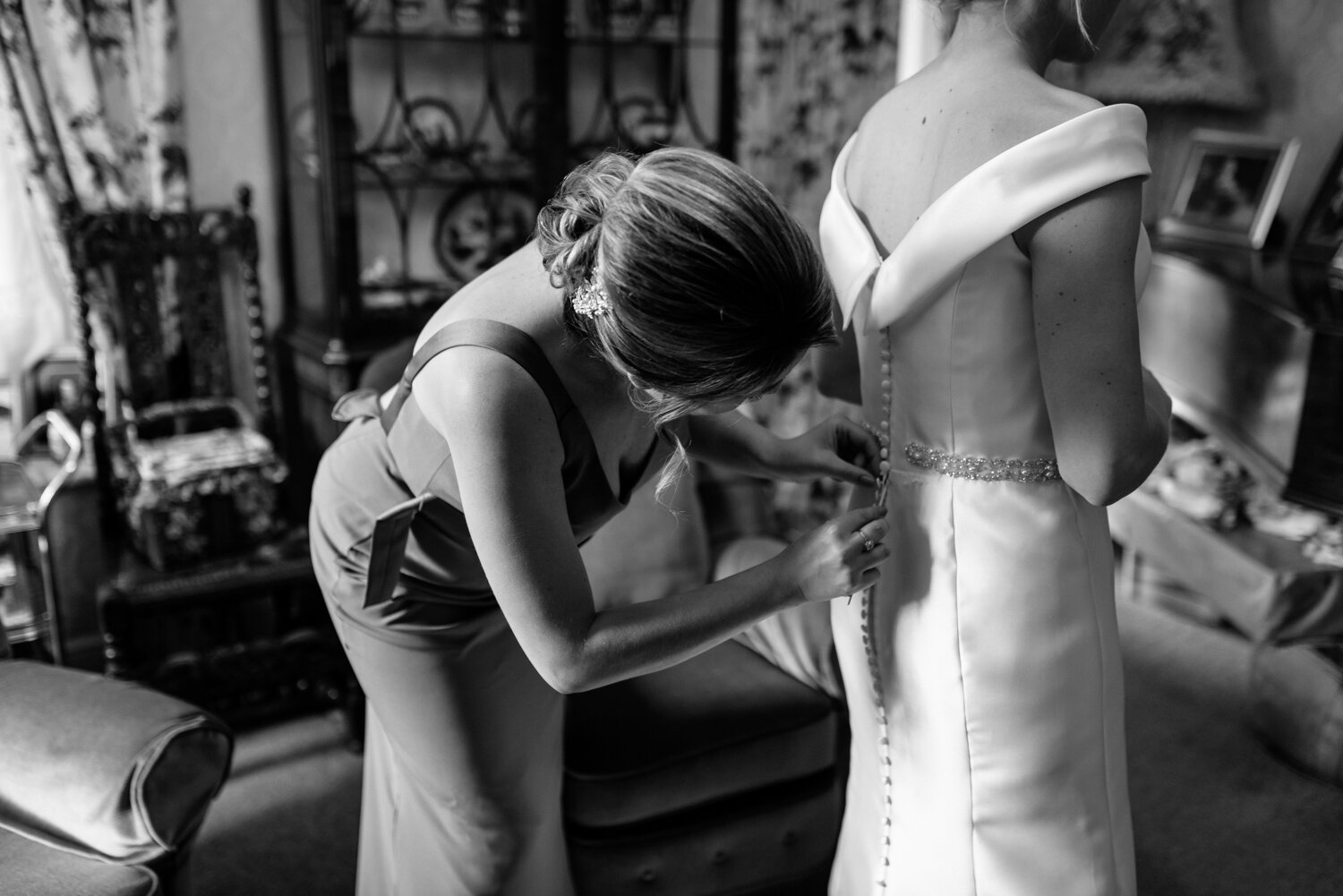 Bridesmaid tying up back of wedding dress