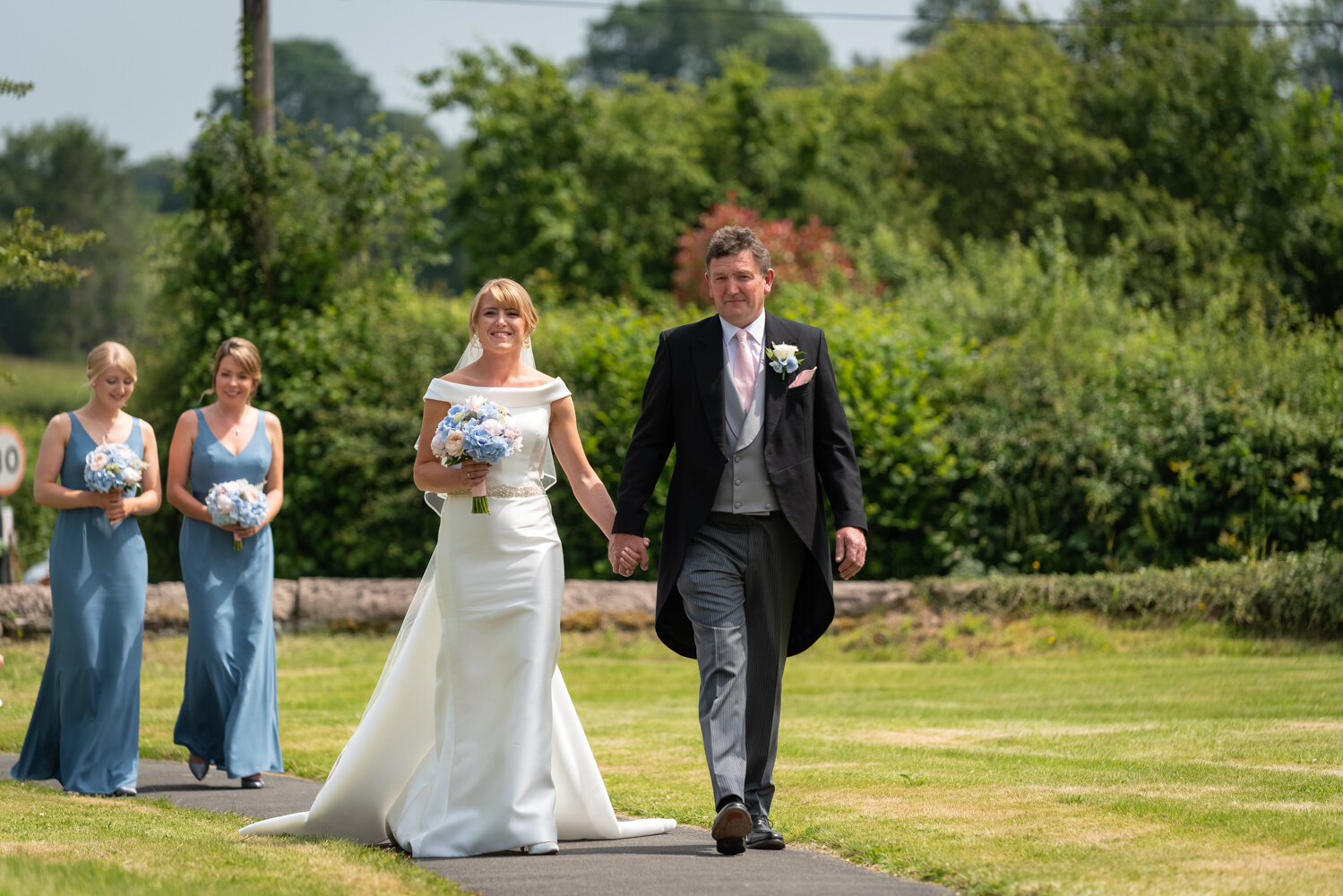 Bride and father walking up path to Glasbury church