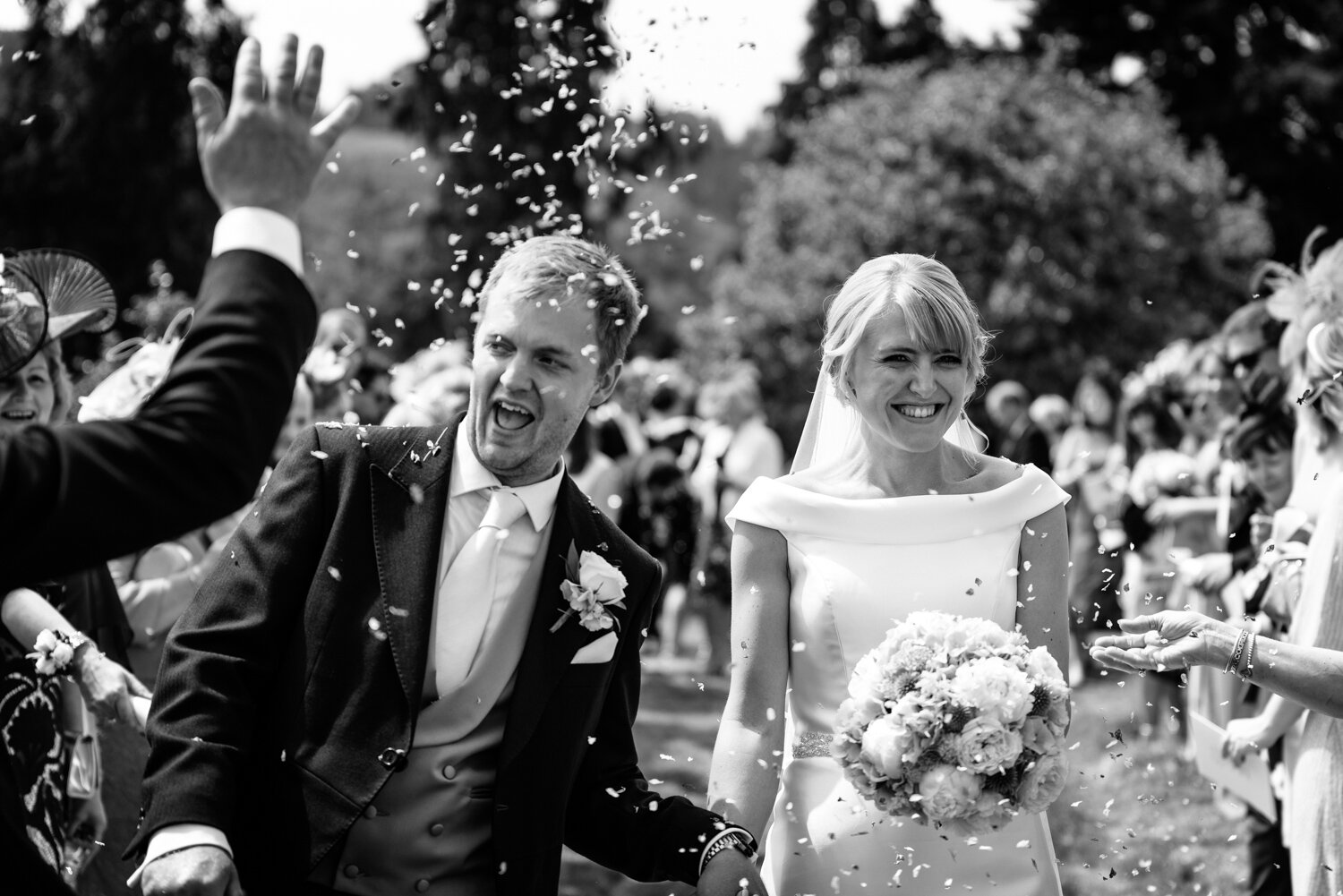 Bride and groom walking through confetti at Glasbury church