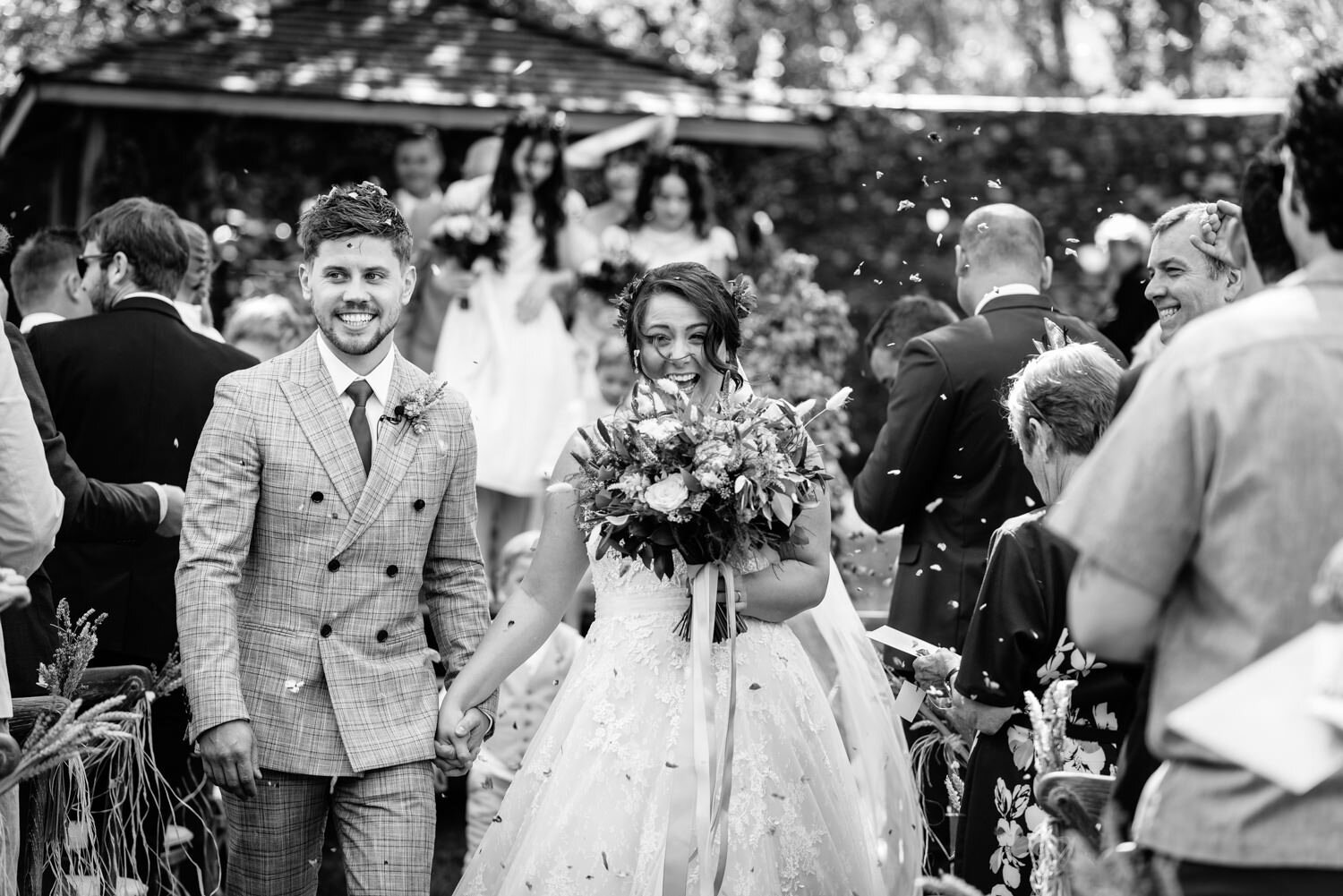 Bride and groom walking through confetti at Tall John's House