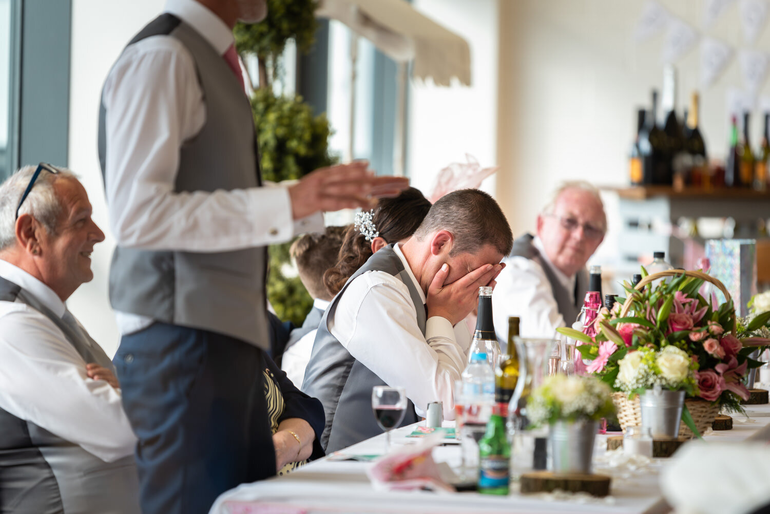 Groom holding head in hands during best man speech