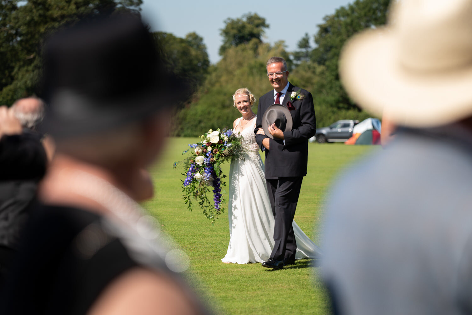 Bride being walked in by father during outdoor Cheshire wedding.