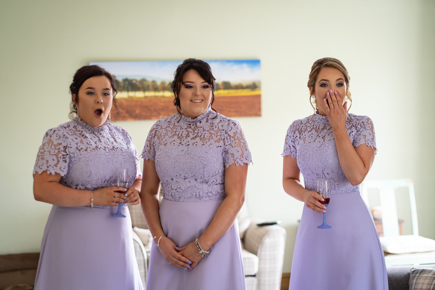 Shocked bridesmaids seeing bride for first time in wedding dress