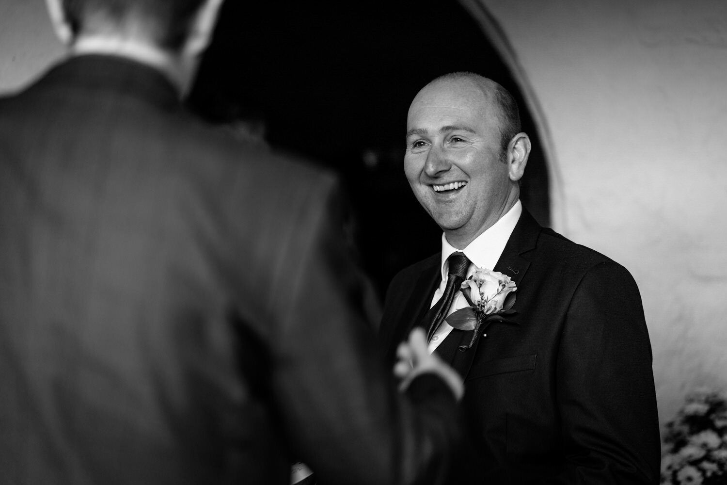 Best man laughing greeting guests at church 