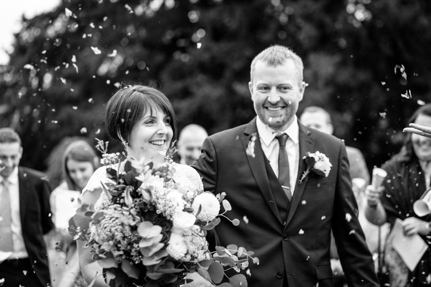 Bride and groom laughing as confetti thrown
