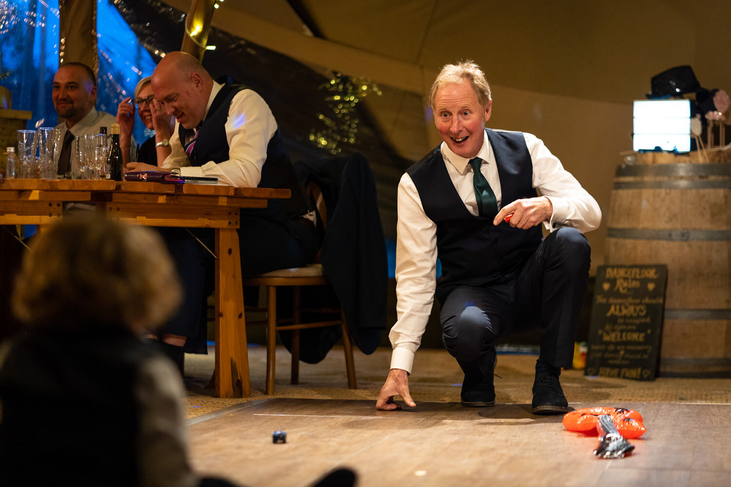 Father of bride playing with children at wedding reception