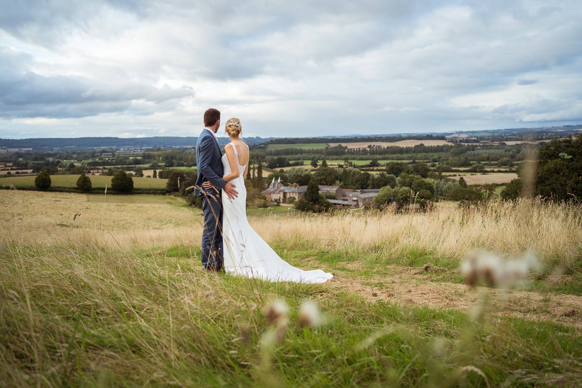 Bride and groom on hill over looking Lyde Court