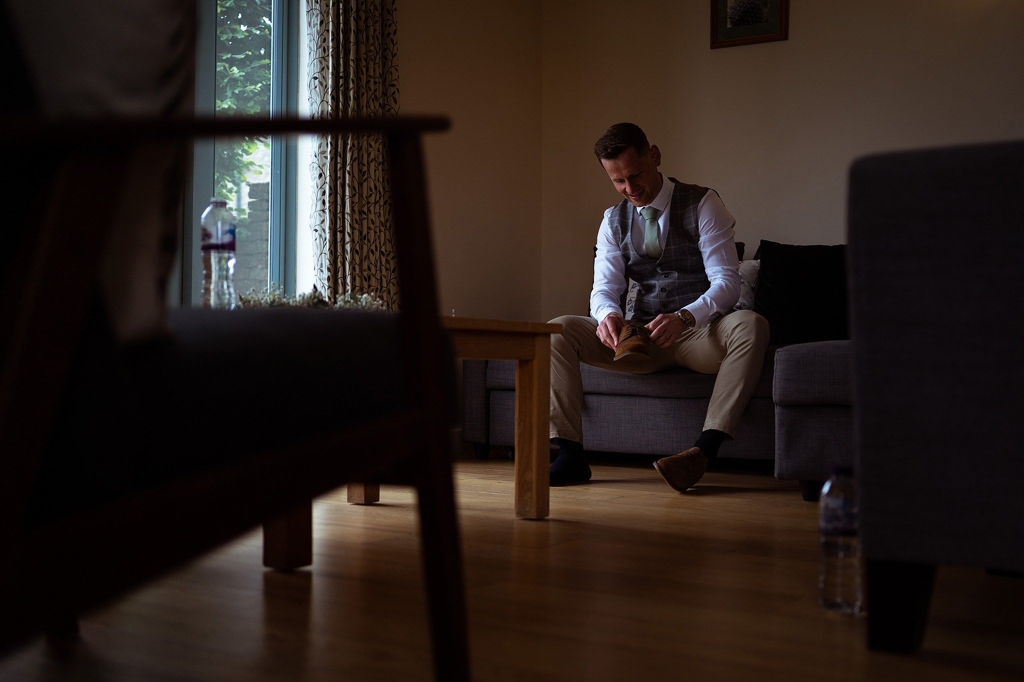 Groom putting shoes on before wedding