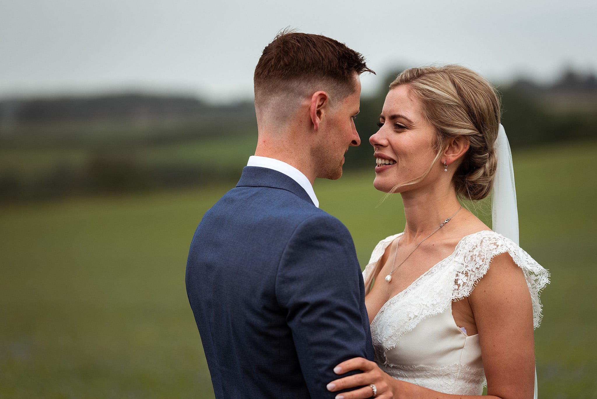 portrait of groom and bride in field at Kingscote Barn