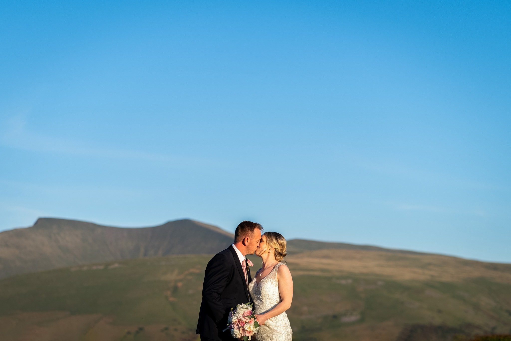 Bride and groom kiss in front of Brecon Beacons