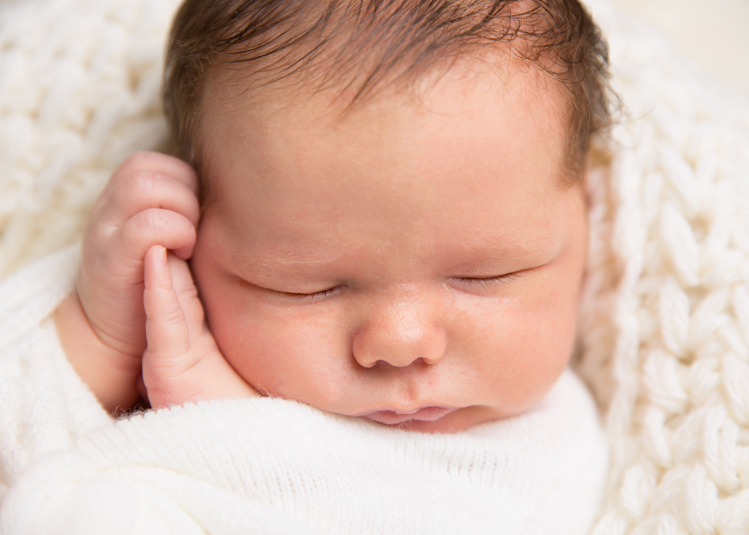 newborn-sleeping-baby-on-back-hands-by-cheek
