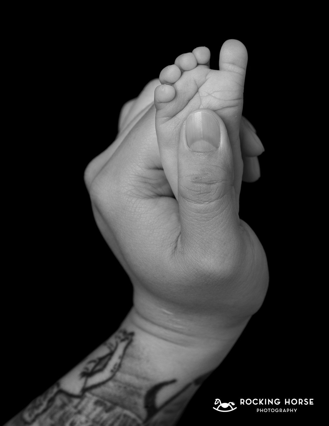 Black-and-white-image-babys-foot-held-in-dads-hand