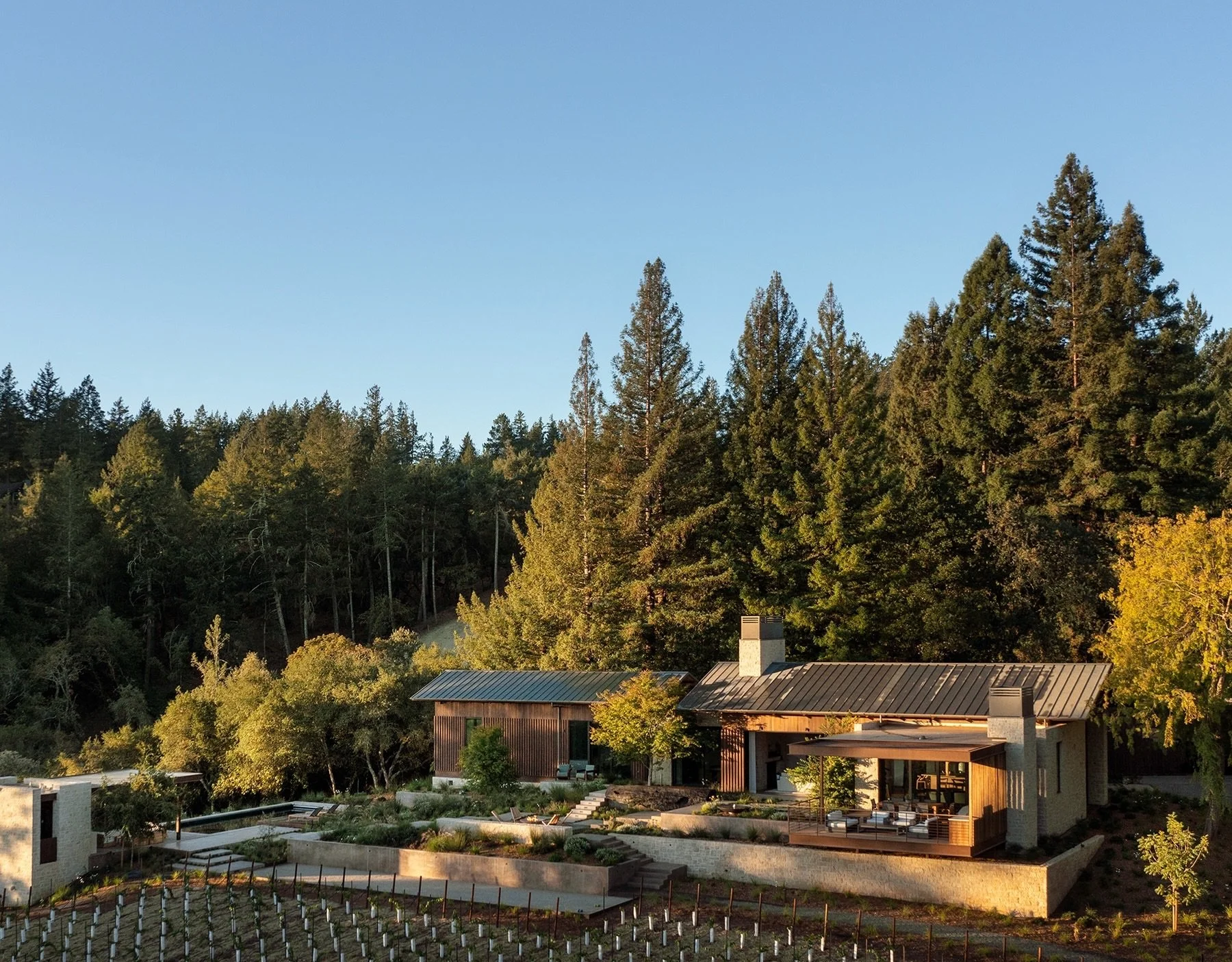 Our Dry Creek project greets the morning sun while nestled into the base of the Jack Pine forest.  Morning dew still glistens on the standing seam steel roof.
Cascading patios rest gently on the landscape finding their way to the pool deck below, off