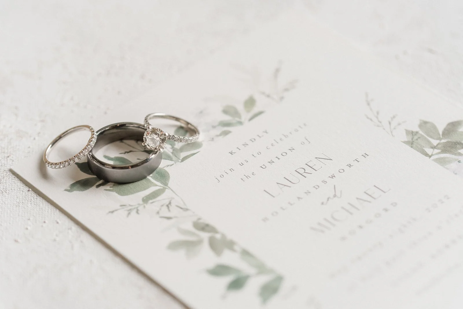 Bride and groom's rings on top of wedding invitation