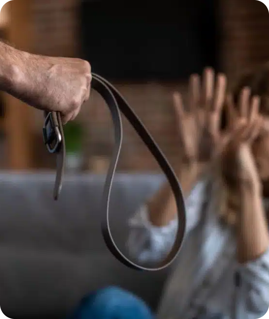 A person holding a belt in front of a frightened child with hands raised and eyes wide open.