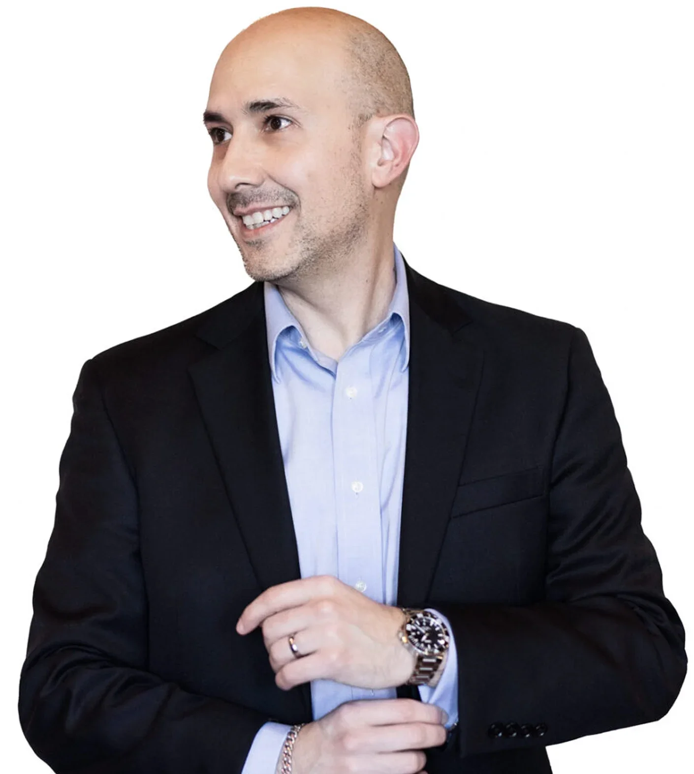 A bald man wearing a black suit jacket and a light blue button-up shirt, smiling and looking to the left, with his arms crossed in front of him.