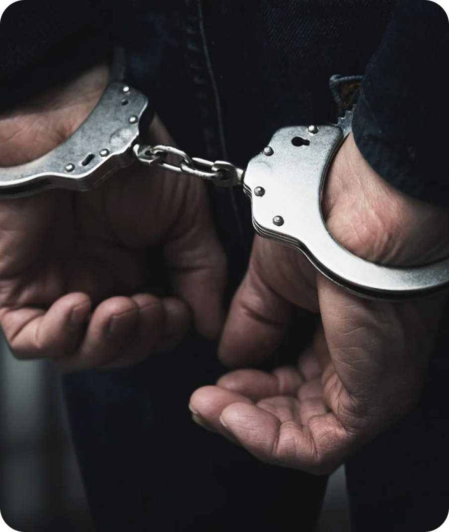 A person wearing black jeans with hands in handcuffs, holding the cuffs together.