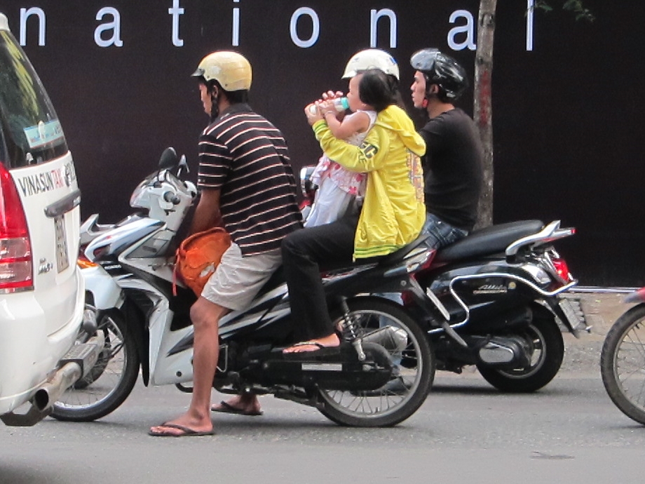 You see lots of infants and toddlers standing, sitting or hanging off of motor bikes--it's bottle time for this one.