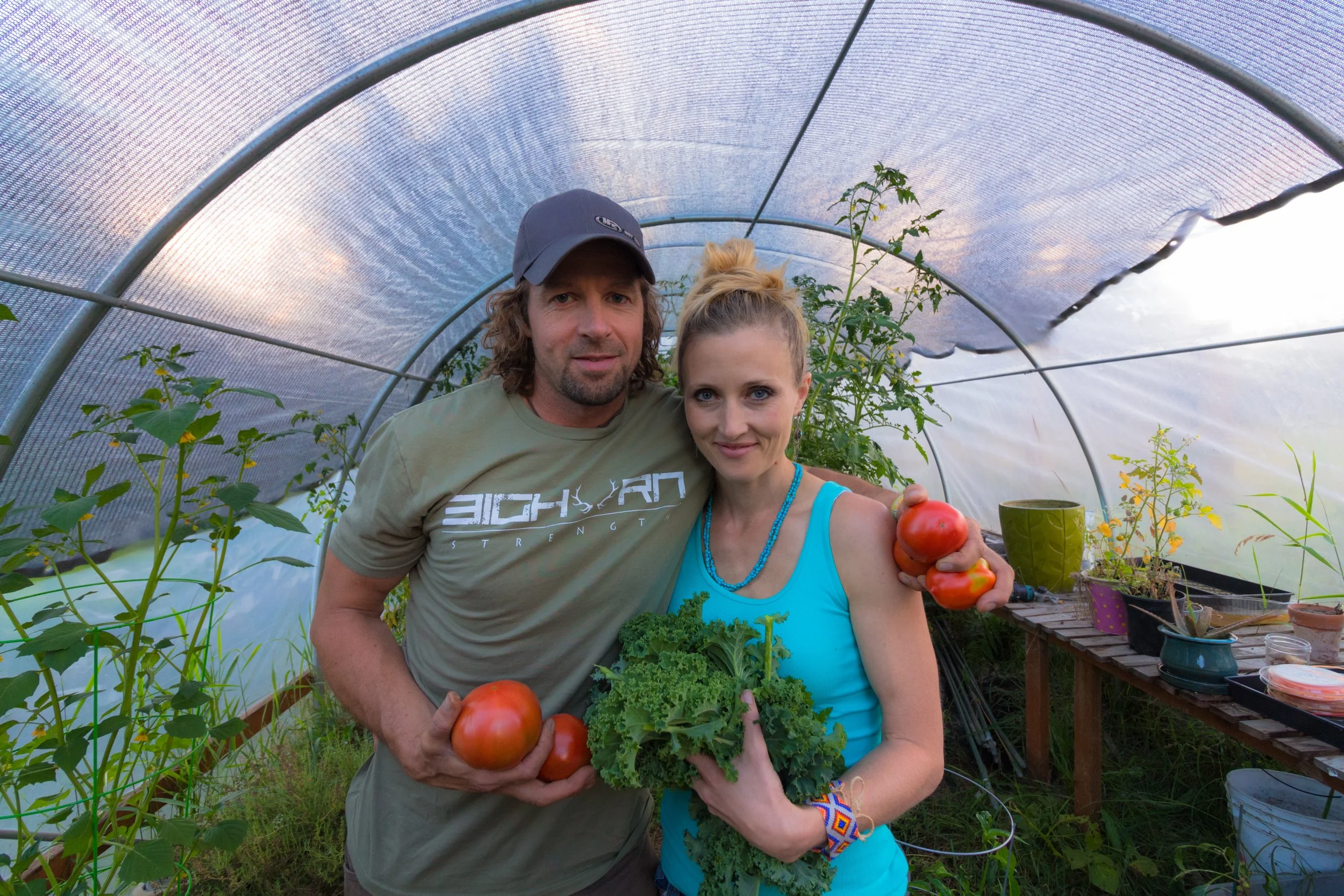 Ryan and Hillary in the greenhouse with a late summer tomato harvest Picture by @_sly_slyvester Ryan's Tshirt @bighornstrength