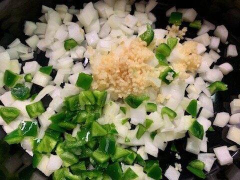 Onion, jalapeno pepper, and minced garlic added to the bottom of the crockpot.