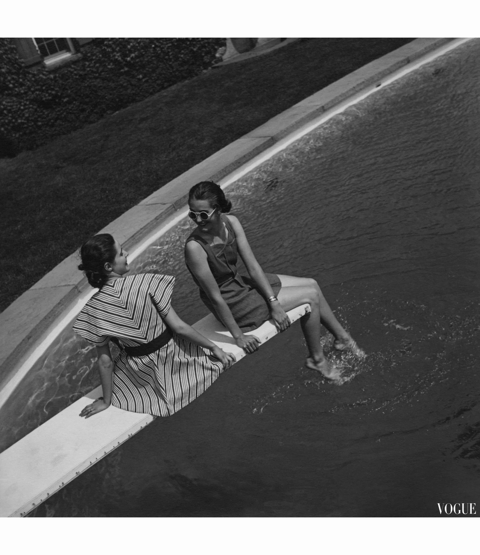 two-models-sitting-on-a-diving-board-and-wearing-left-to-right-a-flared-tunic-with-chevron-stripes-and-a-stitched-blue-denim-bathing-suit-with-white-jersey-shorts-toni-frissell-vogue.jpg