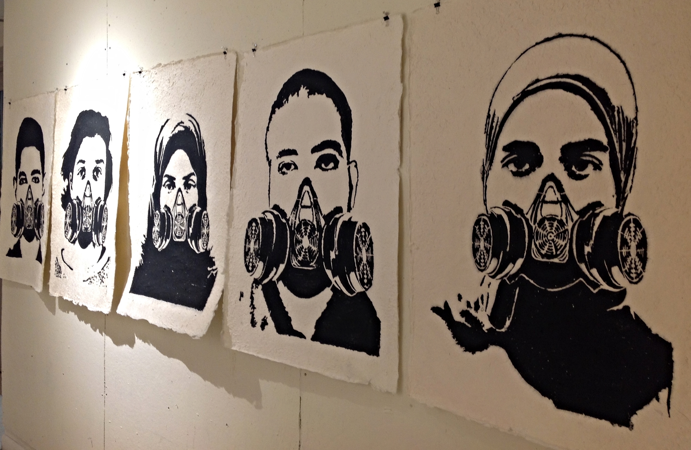 During the Egyptian revolution, graffiti played a seminal role in the depiction of public perceptions of events. The streets served as a live platform where people voiced their opinions on many political and social issues. The graffiti was born within the dust and dirt, the crowded bustle and messiness of the city of Cairo. During the revolution, graffiti mimicked the highly fluid, often volatile scenes of Egypt at the time. It was all about symbolism, using minimal text and image to send direct, easily understood and recalled messages. Painting on the walls, stenciling and other art forms were often far more powerful and challenging than mainstream media. My work is a response to the graffiti covering the walls on Mohamed Mahmoud Street, a street that witnessed many of the now historically documented massacres. Local people, artists and activists documented and recorded these massacres by painting the portraits of the people who died on that street, turning the site into a graveyard commemorating their loss. The walls became invisible behind the images, allowing artists and viewers to break through all physical boundaries, cross over fictive borders, the imaginary ‘lines in the sand’ separate truth from illusion. The graffiti reminded viewers that what was once ever-present had disappeared and gone. The handmade paper used in this exhibition brings to life those portraits while the gaze and stare of each face confronts the viewer, questioning reality. The series of portraits displayed here together in a row, simulates for the viewer the experience of that dramatic moment of history on Mohamed Mahmoud Street. Graffiti became a weapon and an echo of the past as it memorialized the people who died and the place of their sacrifice. This exhibition attempts to connect this historical moment to the present, as people continue to fight for their rights and for a genuine Egyptian democracy. 