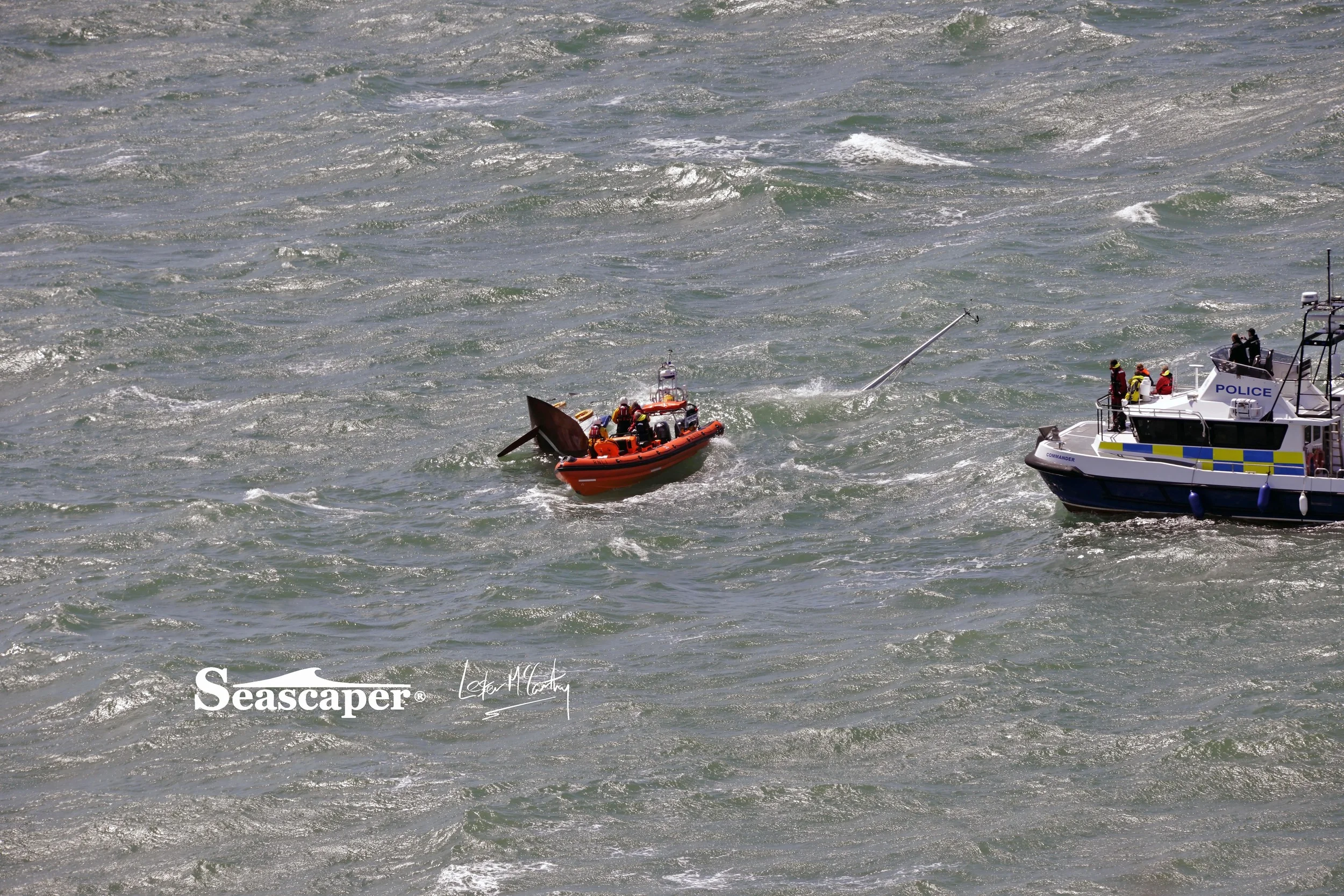 Crew members watch from Commander as their yacht Alchemist sinks.