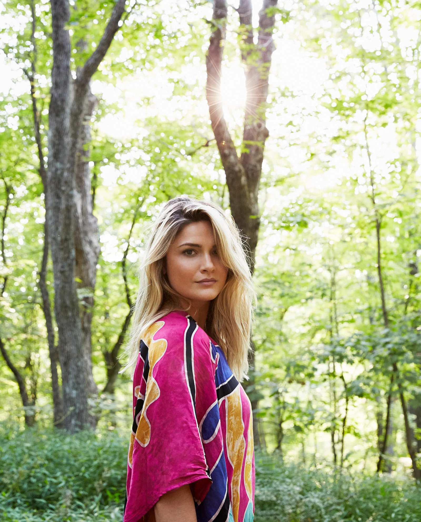 portrait of blonde woman in woods near golden hour