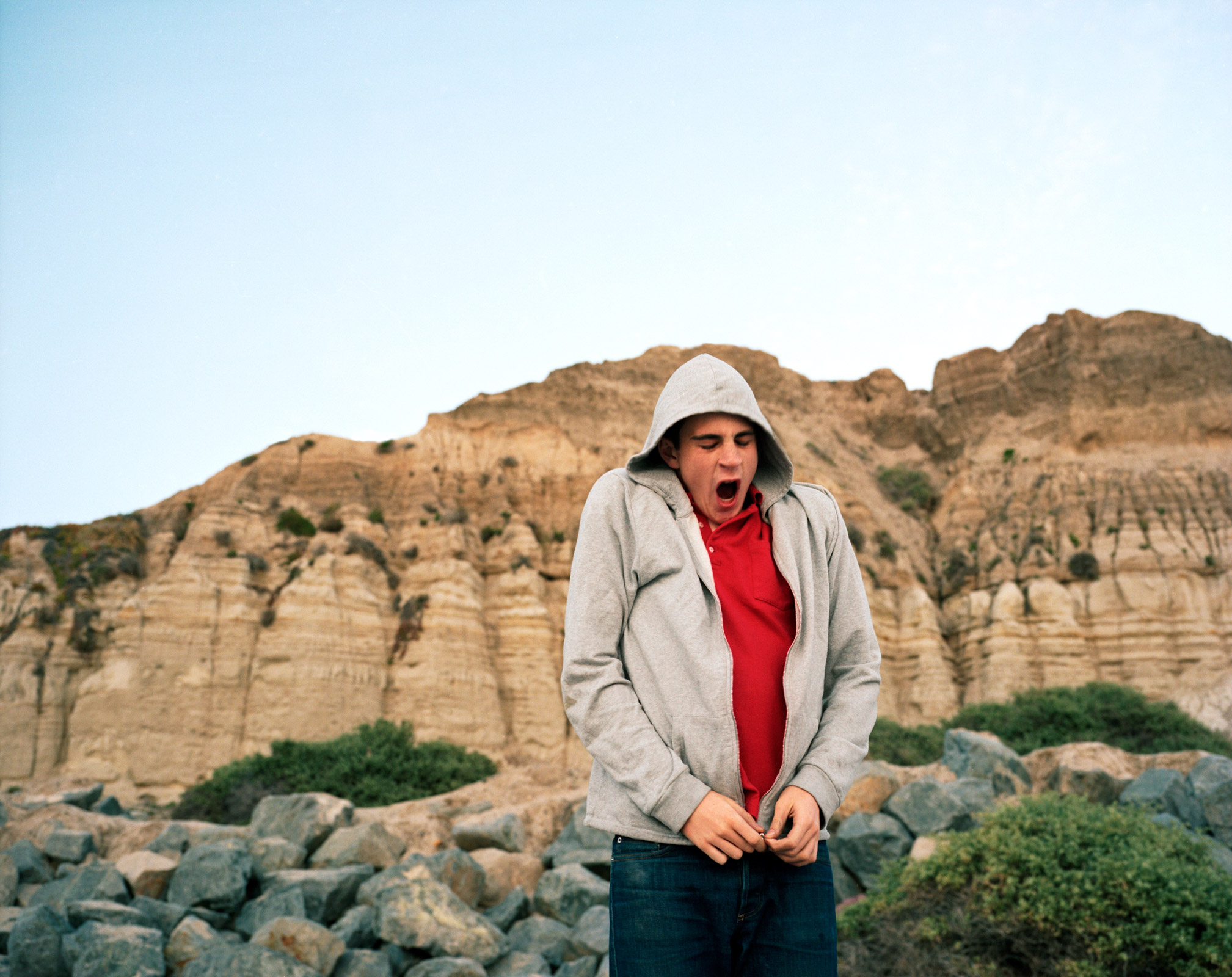 man zipping up sweatshirt and yawning in yosemite park