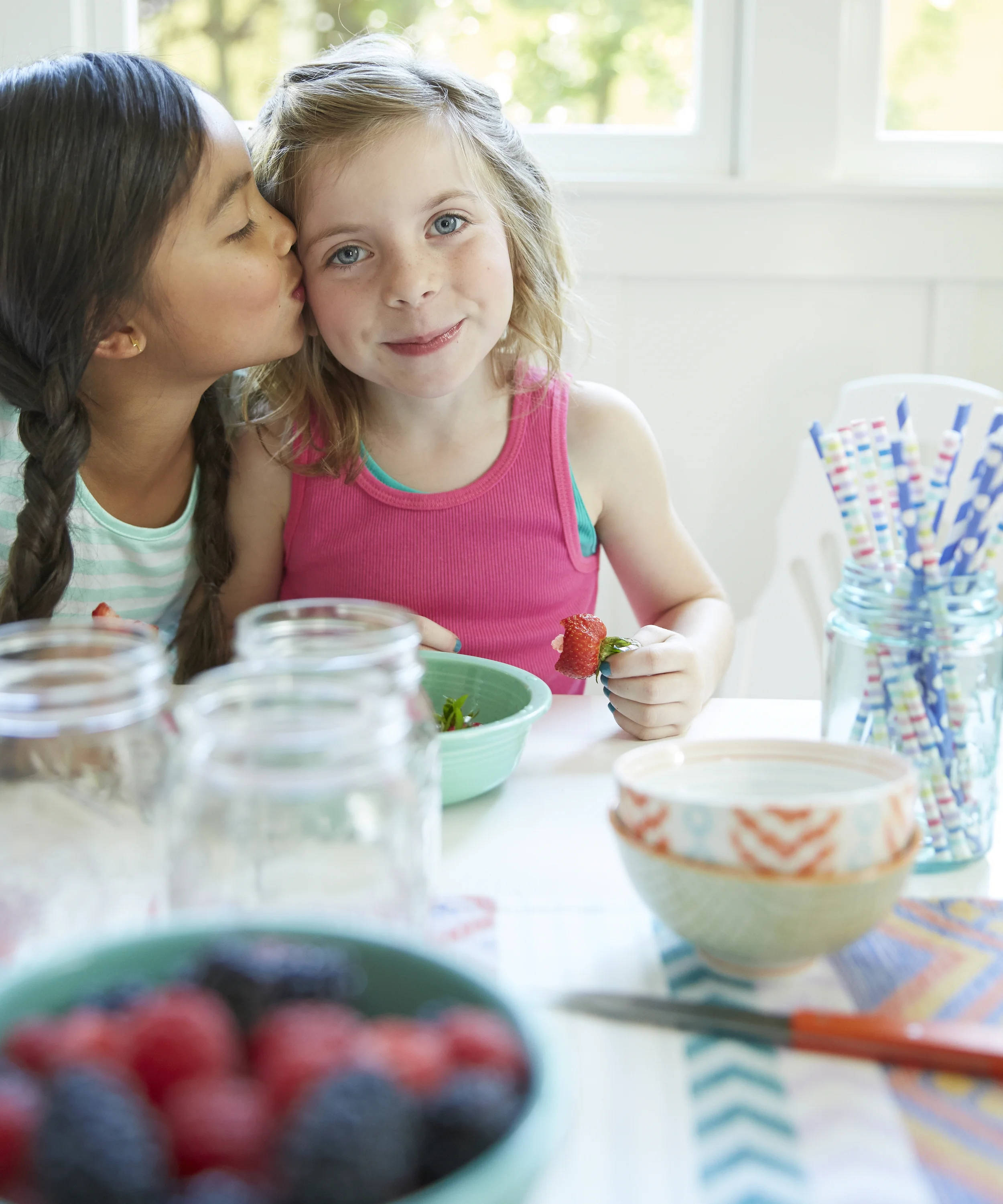 girl giving her friend a kiss at the lunch table