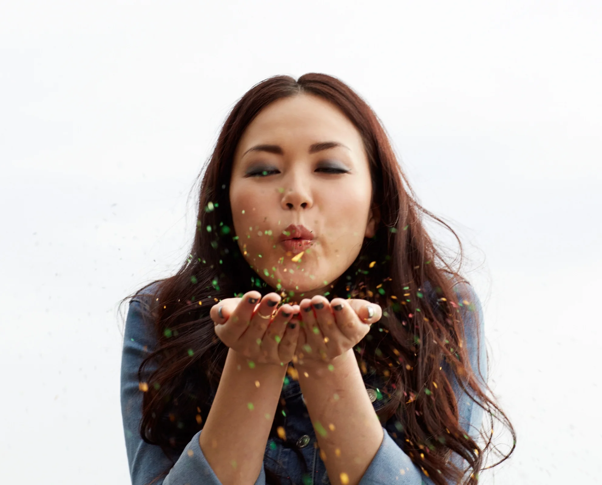 woman blowing glitter from palms of hands to make a wish