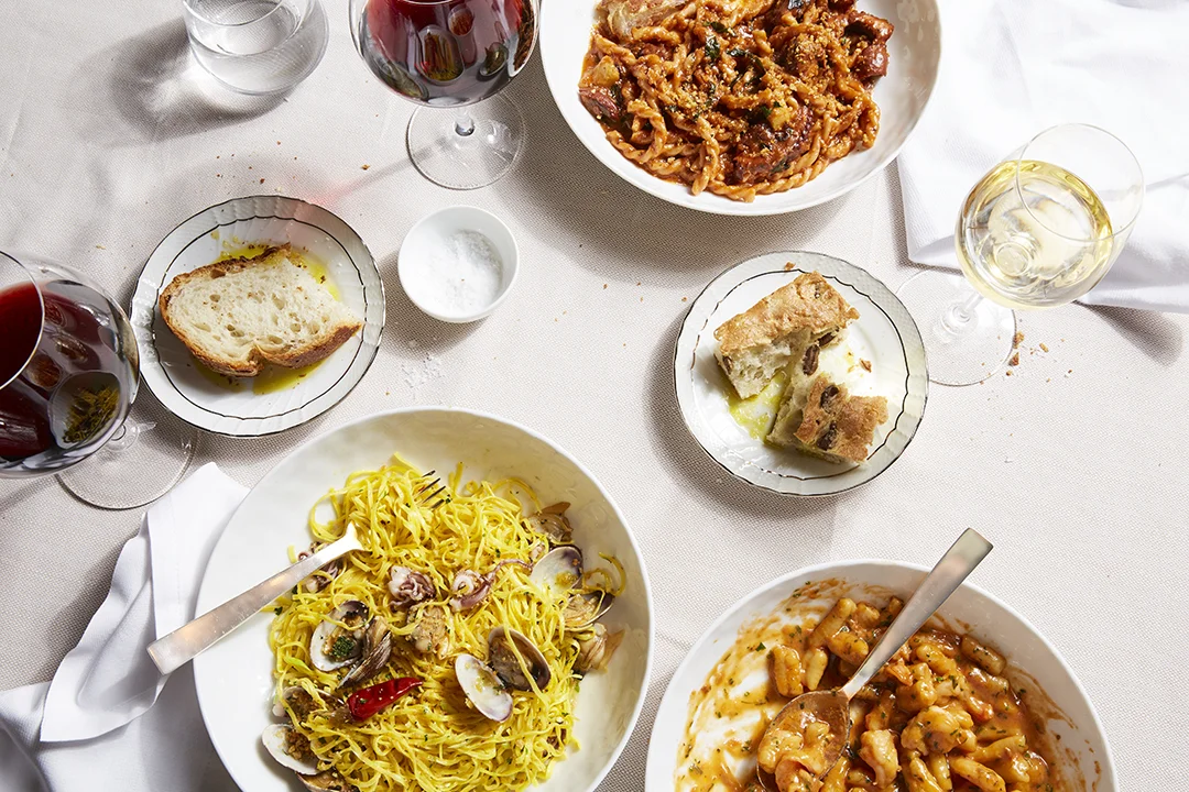 Restaurant table full of pasta, bread and wine