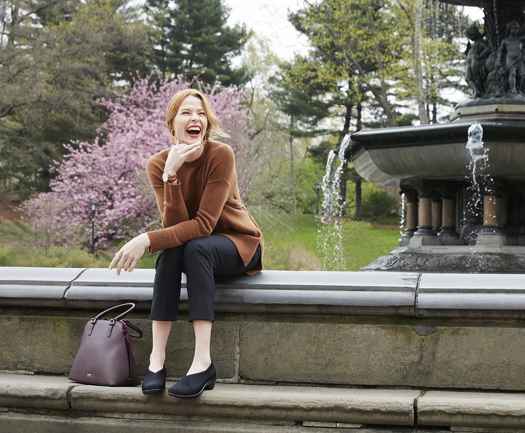 Woman laughing while sitting on a fountain