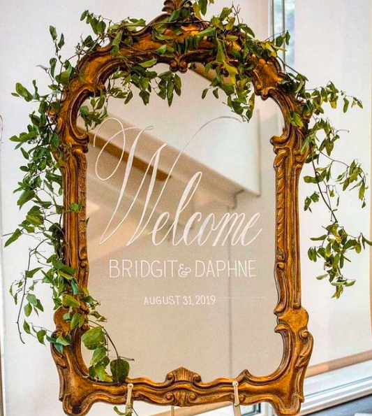 Our ornate gold mirror with white calligraphy on gold easel with a floral  garland, in the tre…