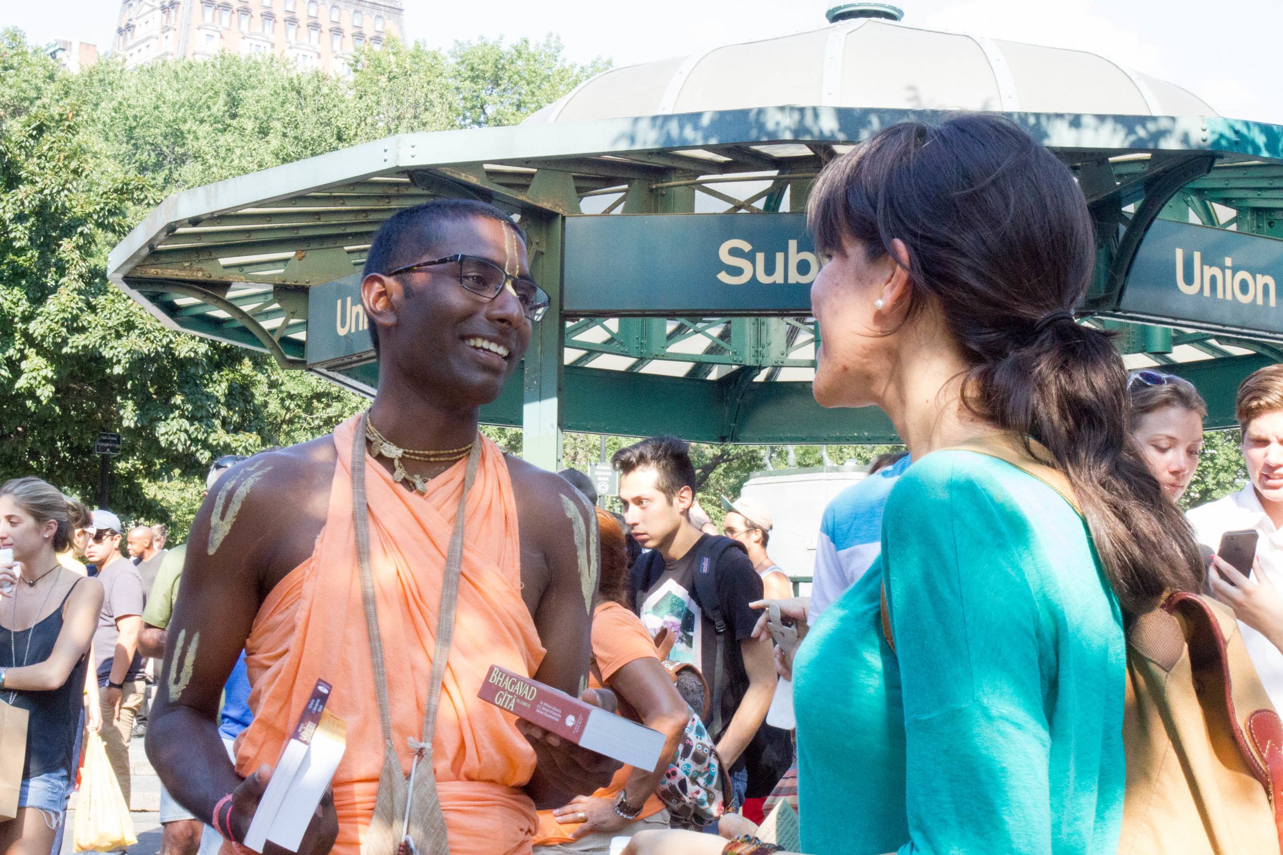 Nihal and a passer-by laugh together as Nihal tries to convince her to accept his book