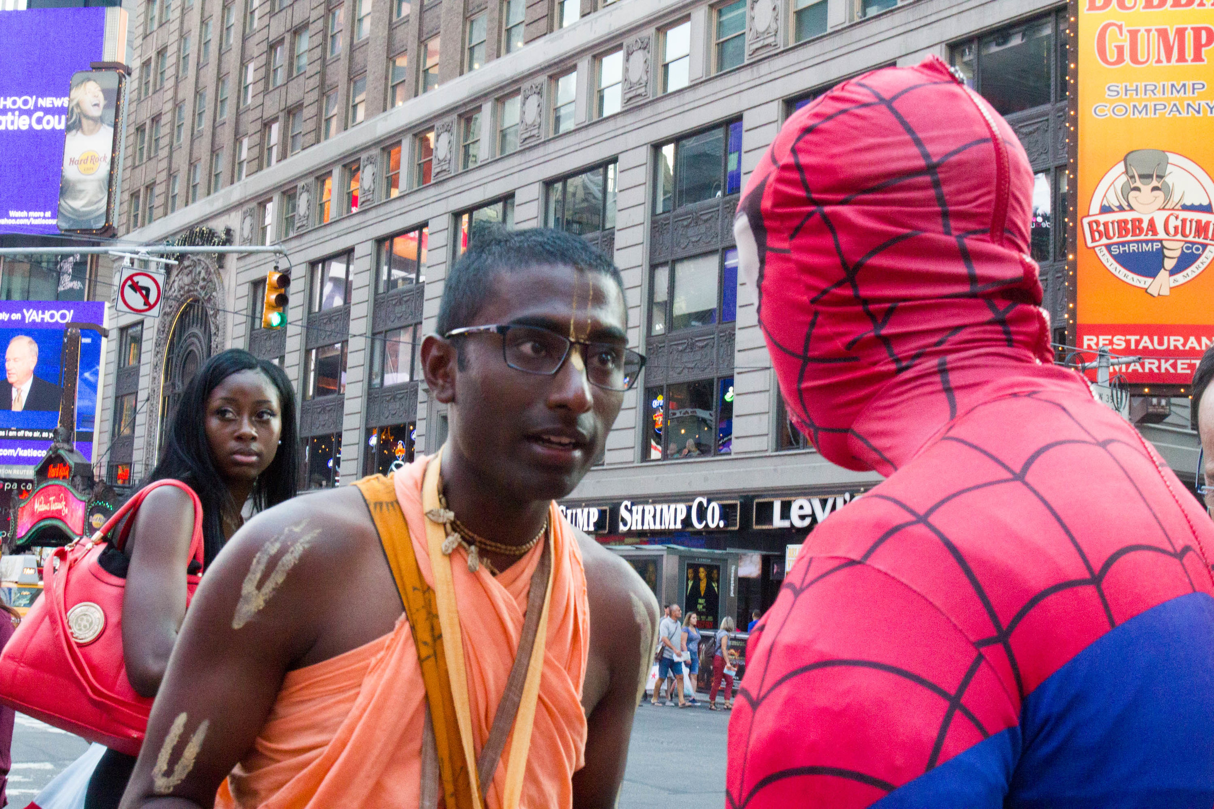 Nihal speaks to a man dressed as spider man while chanting in Times square