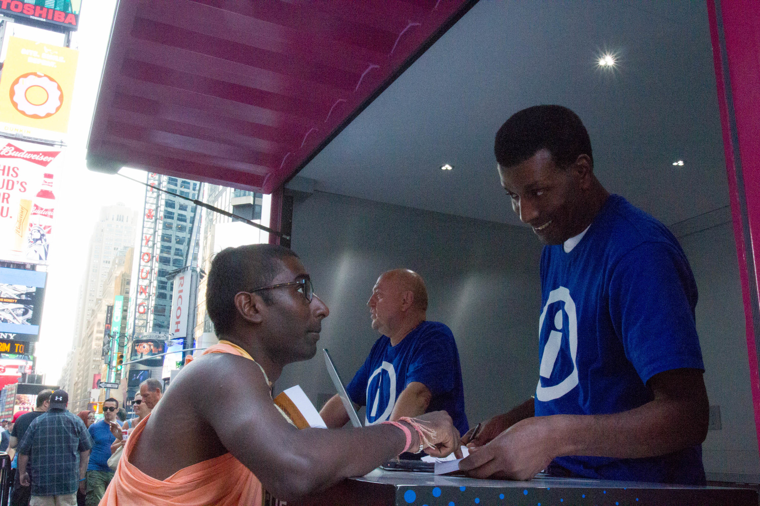 Nihal explains what the Bhagavad Gita is to an information booth staffer in Times Square