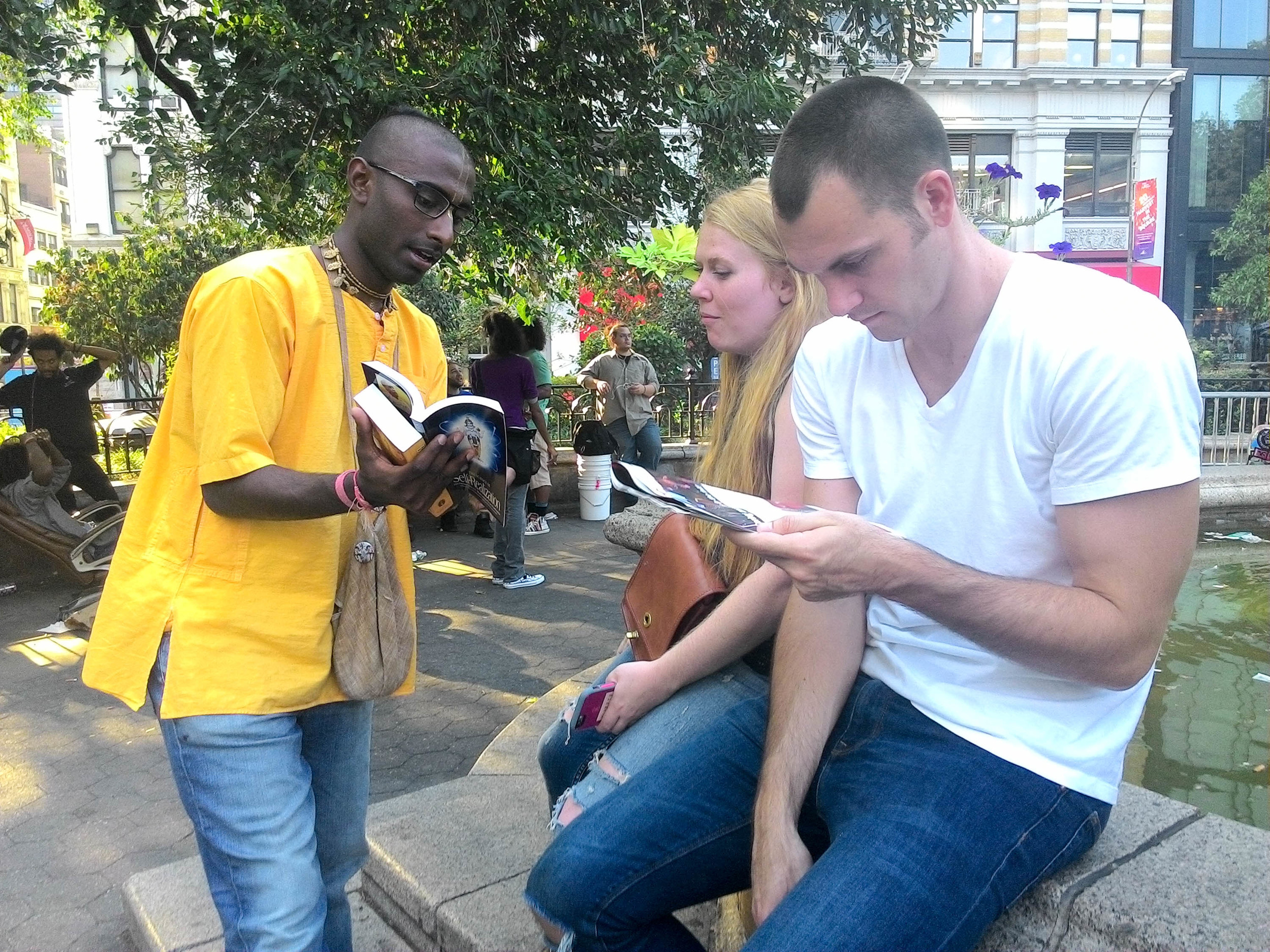 Nihal explains the core teachings of the Bhagavad Gita to a German couple sitting by a fountain