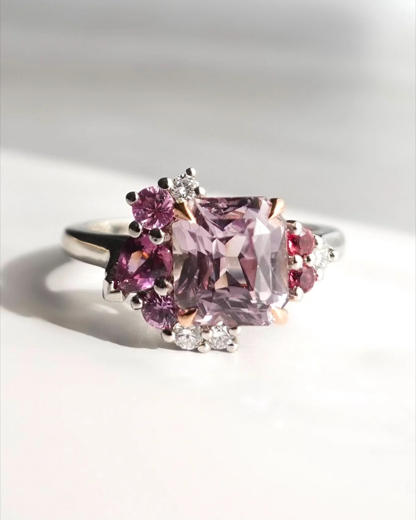 What a beautiful ring - it’s a chameleon. It looks totally different in every light condition. The sapphire is technically peach, but in my light box it looks lilac. In the sunlight in looks peach, indoors it looks champagne. The side gems too