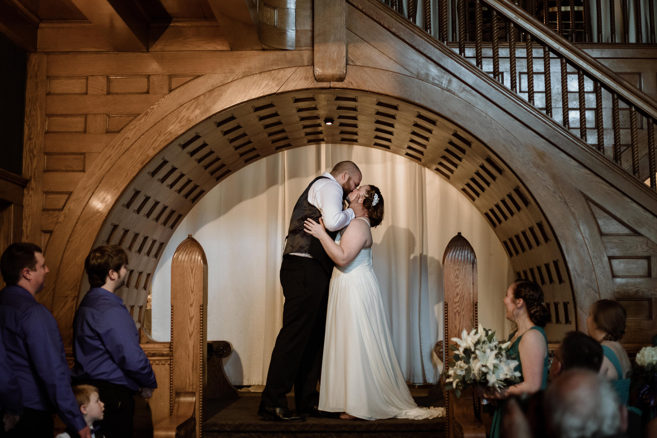 First kiss in wedding ceremony arch at Glover Mansion in Spokane, WA