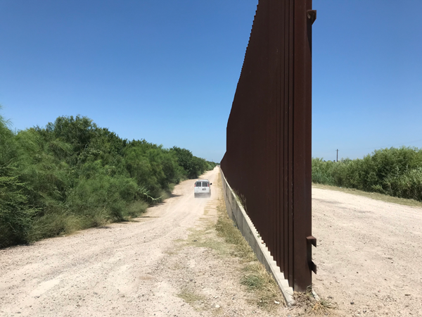 A Border Patrol vehicle travels down the road past the wall. This is approximately one mile from the actual border with Mexico.