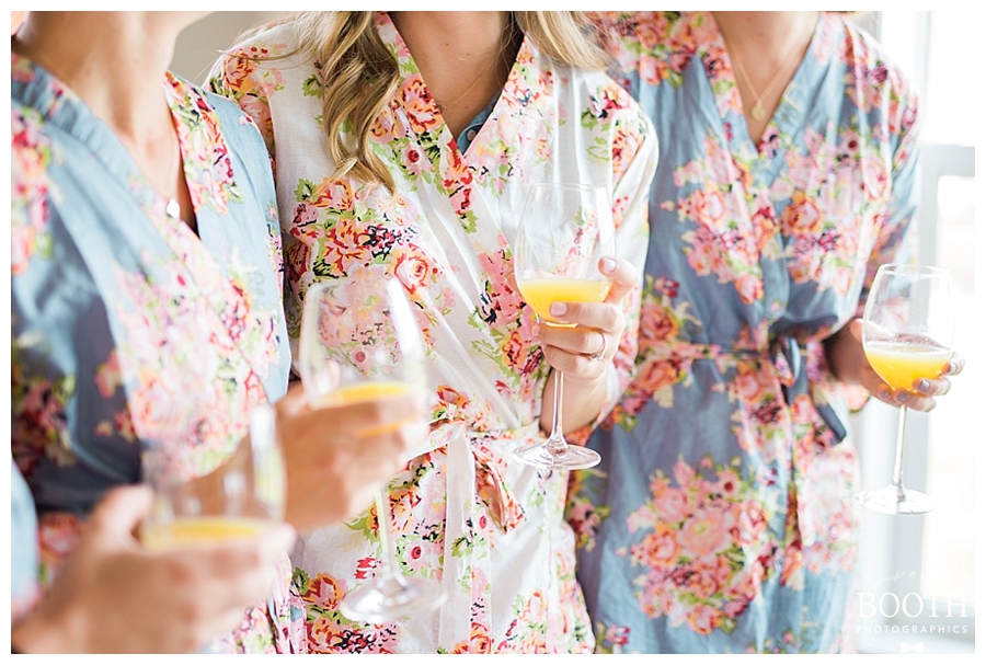 bride and her bridesmaids wearing Plum Pretty Sugar robes drinking mimosas at her rustic outdoor wedding