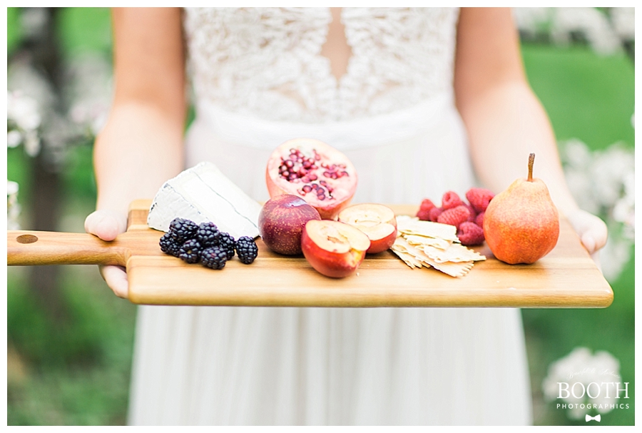 bride wearing BHLDN gown and holding rustic cheese and fruit platter