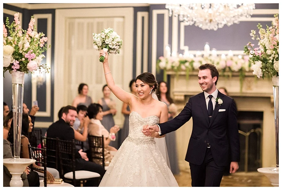 Bride and groom walking back down the aisle during their classic and romantic fireplace wedding ceremony at the Madison Club