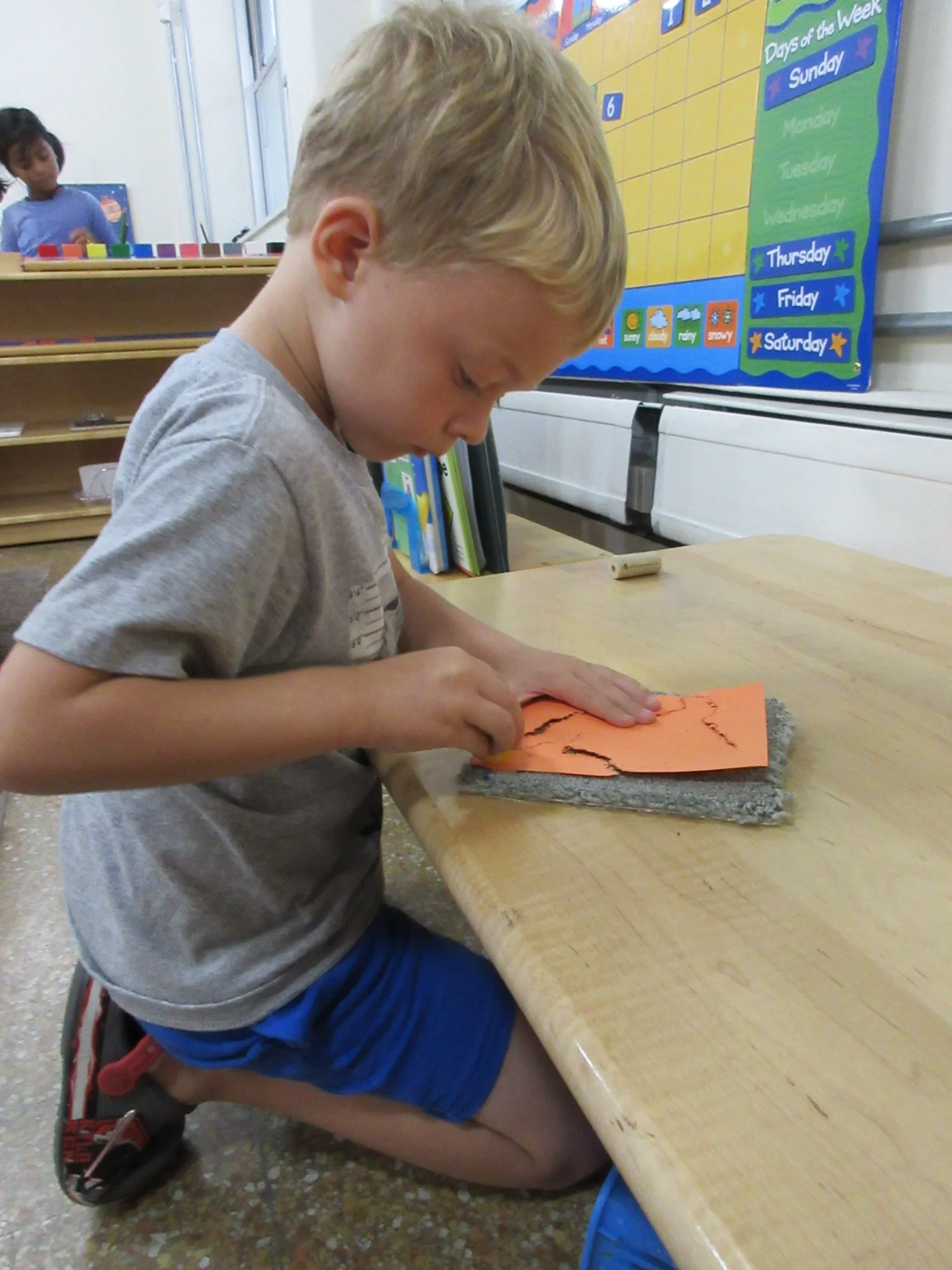 Child using pushpin to outline North America