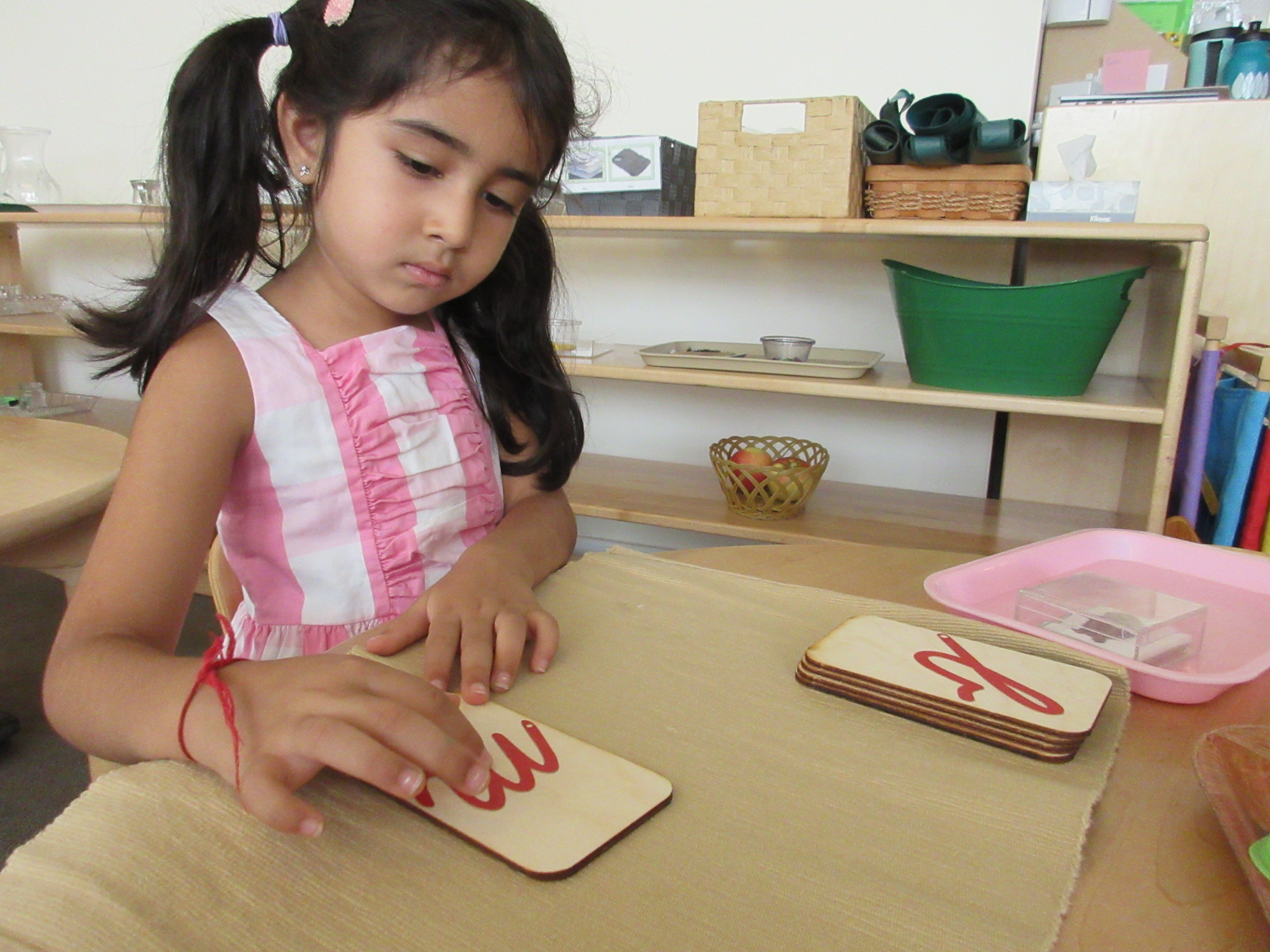 A student uses the Sandpaper Letters to practice her letter sound correspondence.